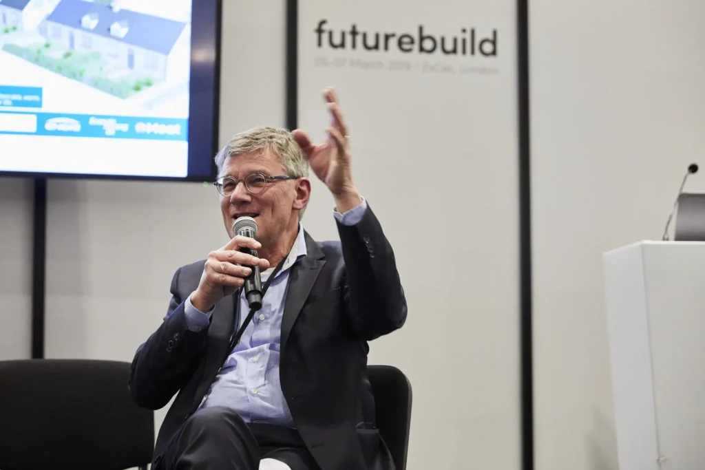 A keynote speaker holds a mic and gestures during a previous edition of the FutureBuild event.