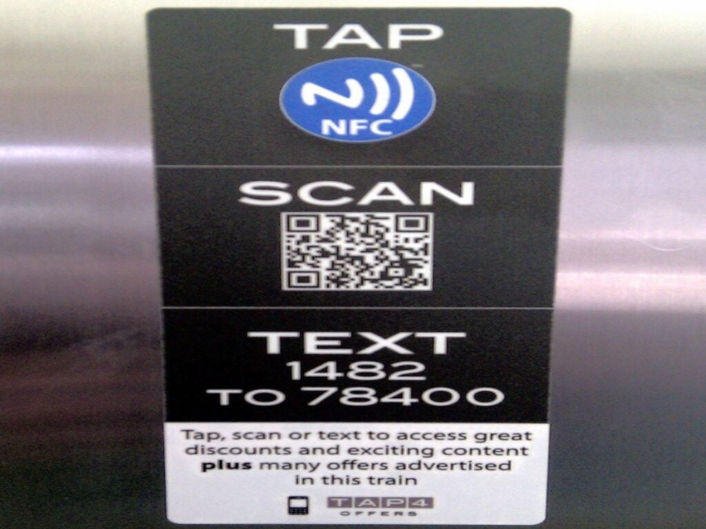 A sticker encourages people to access discounts by scanning a QR code, texting a number, or tapping the embedded Near Field Communication (NFC) chip. 