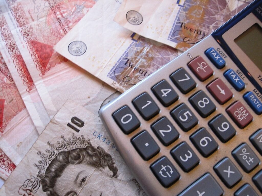 A calculator placed atop some British pound notes. 