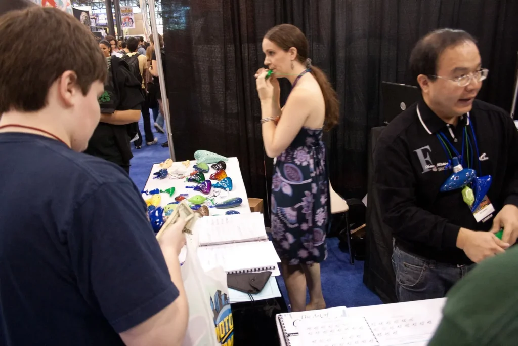 People interacting with staff at a small trade show booth.