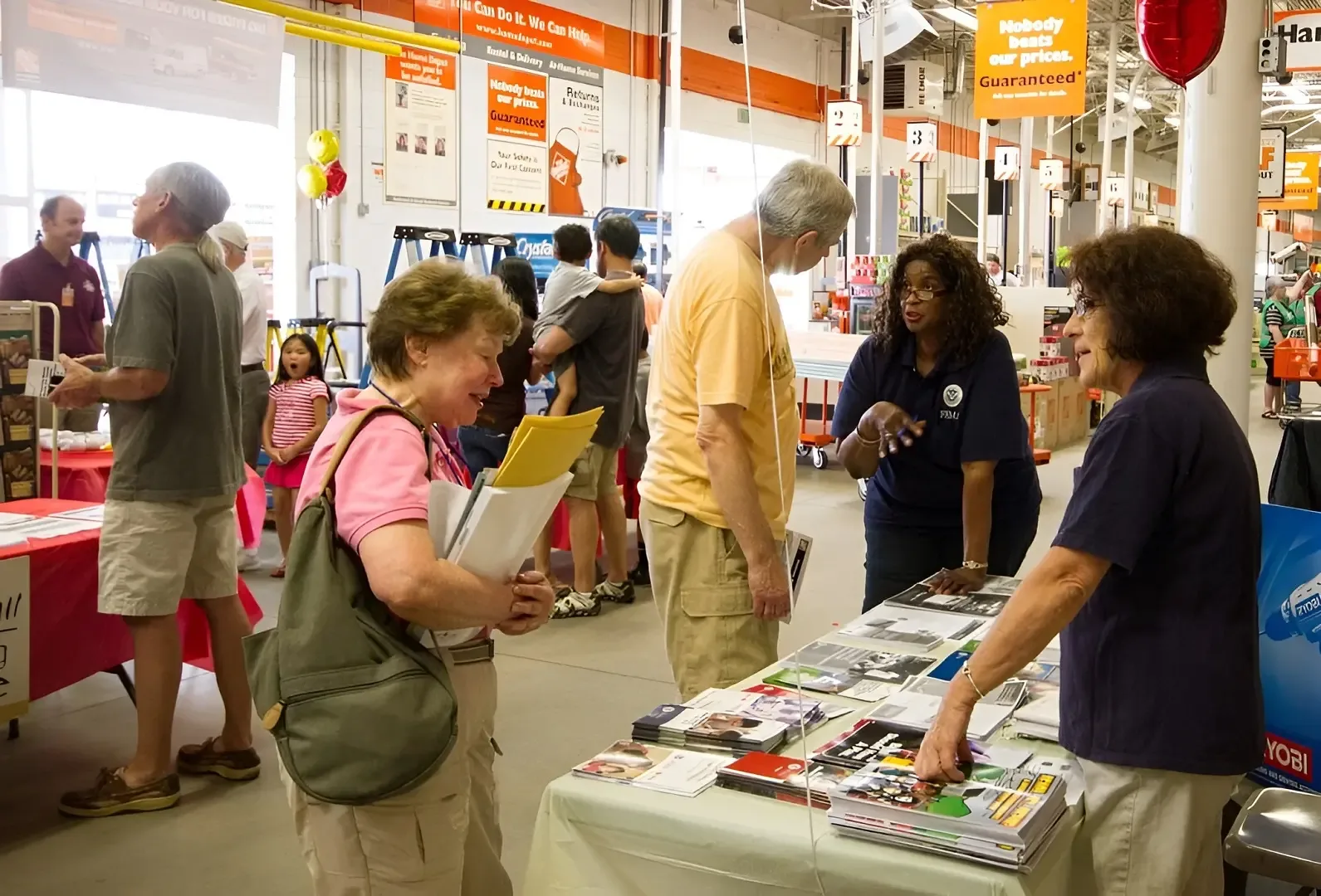 Sales representatives talk with two visitors at a professional trade show stand.