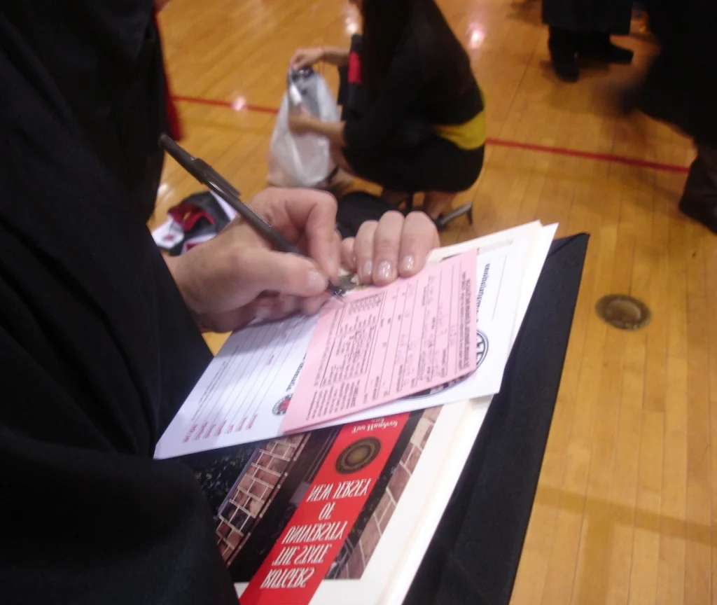 A person writing on a pink slip.