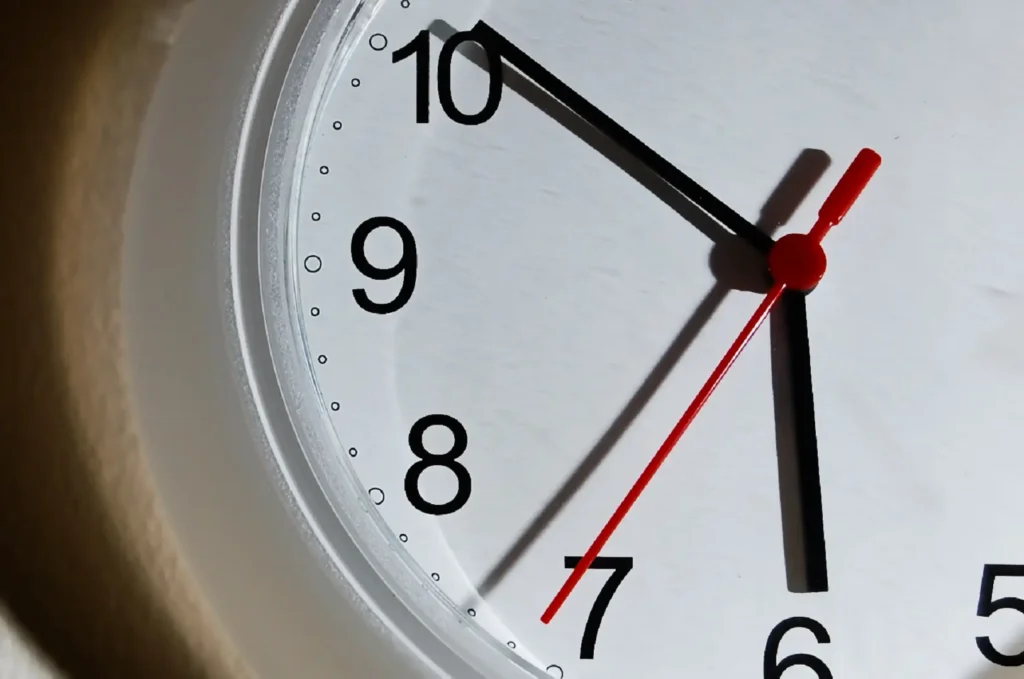 A clock with two black hands for the hours and minutes and a red hand for the seconds. 