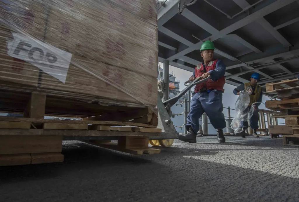 Workers handling pallets at dock.