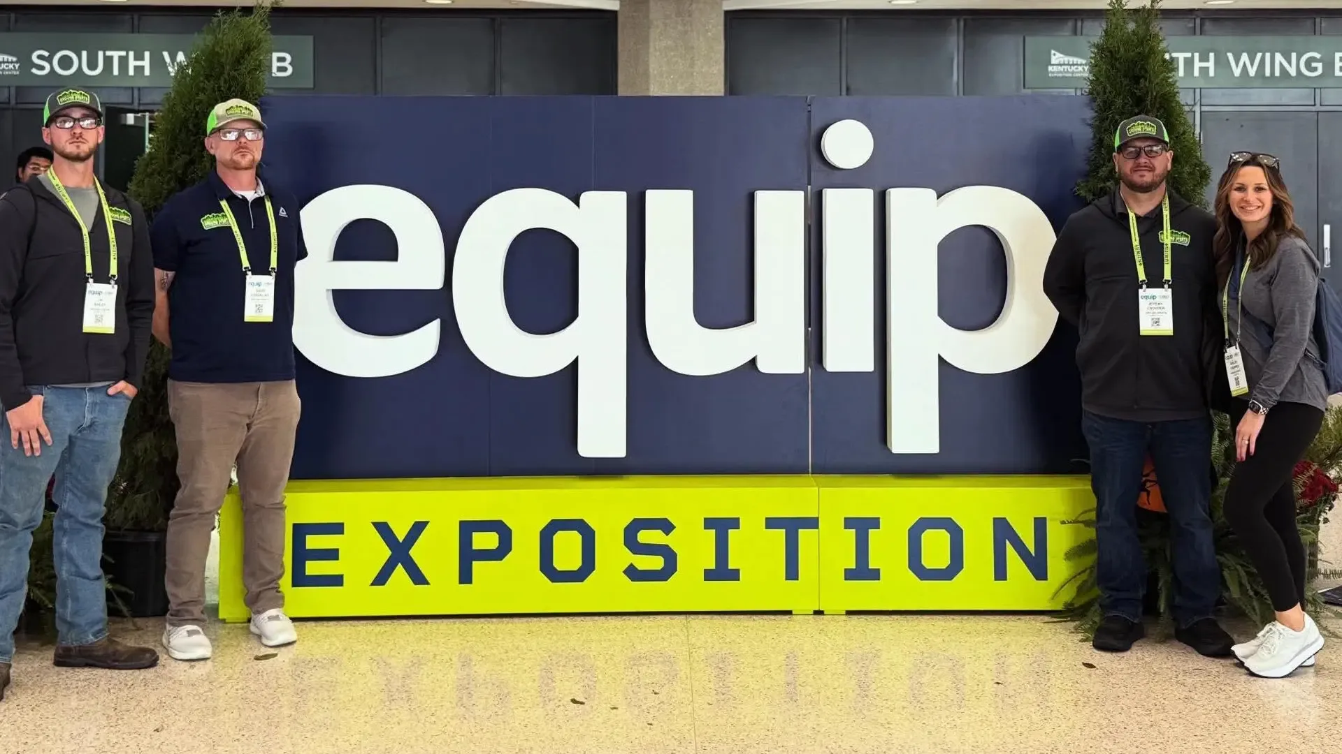 Four attendees standing next to an Equip Expo banner.