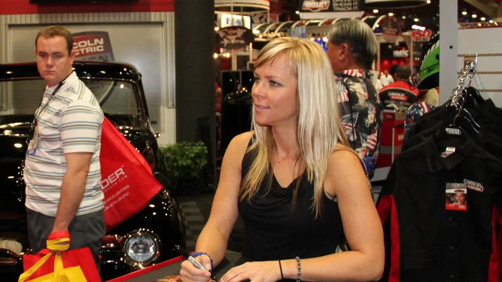 Driver Jessi Combs talking with guests at a SEMA Show event.