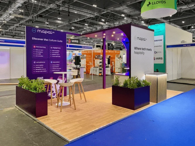 MapalOS purple white trade show booth with wood flooring and planters